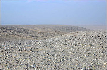 View from the top of the spur (visible in the middle distance in the previous image) that juts out from the plateau beyond the south-east of the Stone Village, back onto the site. The black circles mark the line of an ancient roadway running east-westerly across the plateau here. 